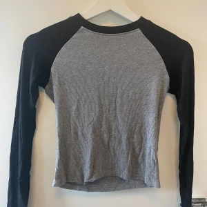 Grå och svart långärmad 2000s tröja - Fin långärmad tröja med grå kropp och svarta ärmar. Passar XS-S, skickar iväg snabbt. Skriv om du har några frågor (har ingen bild med tröjan på)