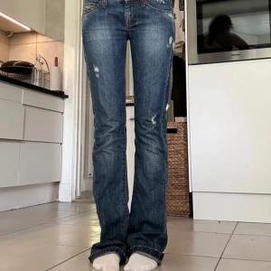 Blå bootcut jeans från Nolita - Snygga blå jeans  med bootcut passform och slitna detaljer. Jeansen har låg midja, klassiska fem fickor. Perfekta för dig som gillar en avslappnad och trendig stil.
