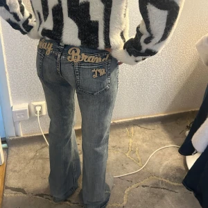 Replay bootcut jeans med brodyr - Snygga ljusblå bootcut jeans från Replay med broderad text i guld på bakfickorna. Jeansen har klassisk femficksmodell, låg midja och cool slitning. Materialet är mjukt denim och passformen är loose nertill.                .               Midja tvärs över- 35 cm lår tvärs över- 20 cm innerbenslängd- 80 cm