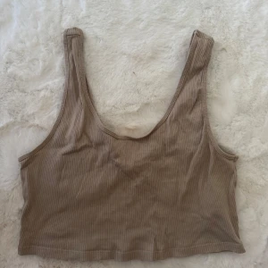 Beige ribbad linnetopp Gina Tricot - Superenkel och snygg beige croppad linnetopp från Gina Tricot. Toppen är ribbad och har breda axelband samt rundad halsringning både fram och bak. Tillverkad i ekologisk bomull, perfekt för varma dagar eller lager på lager.