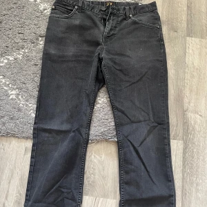 Svarta Rider jeans från Lee W33 L32 - Säljer ett par svarta Rider jeans från Lee i klassisk femficksmodell. Jeansen har raka ben, normal passform och dragkedja i gylfen. Materialet är slitstarkt denim i bomull och de har snygga bakfickor med Lee-logga. Perfekt för dig som gillar stilrena och tidlösa jeans.