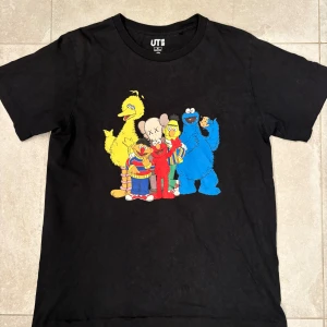 KAWS x Sesame Street Uniqlo svart t-shirt - Svart t-shirt från Uniqlo UT med KAWS x Sesame Street print på framsidan. Relaxed rak fit. (Nypris ca 800kr)
