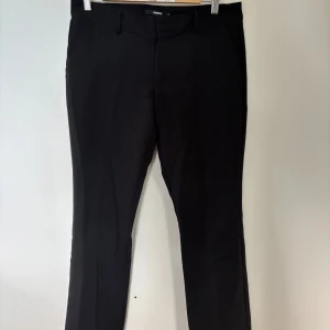 Svarta lågmidjade kostymbyxor från Bik Bok - Snygga svarta kostymbyxor från Bik Bok i modellen Vera. Inte använda så mycket så de är i superbra skick. Storlek 42, lite små i storlek. Säljer då de inte passar längre.