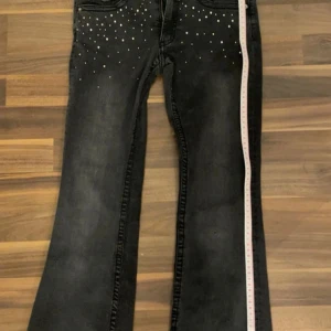 Svarta bootcut jeans med nitar - Svart gråa Lågmidjade bootcut jeans med fina detaljer 💗 Supersnygga fickor! Storlek 32 men passar mig perfekt och jag har strl 34. Använda fåtal gånger men har dock ett jätte litet hål på knäet men syns knappt.❤️ Pris kan diskuteras! Hör av om du har fler frågor så gör jag mitt bästa att svara😊