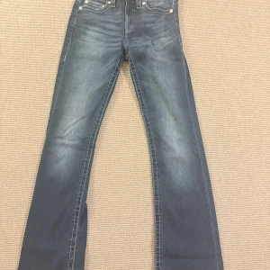 True Religion Becca Bootcut Jeans - Snygga blå jeans från True Religion, modell Becca med bootcut och medelhög midja. Jeansen är i mycket bra skick och är använda fåtal gånger men säljs då de inte används!