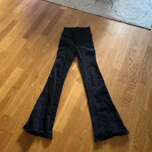 Svarta bootcut byxor med hög midja - Snygga svarta byxor med bootcut och hög midja. De har en tight passform upptill och vida ben nertill, vilket ger en riktigt trendig siluett. Perfekta att styla med sneakers eller boots för en cool look.köptes för 500