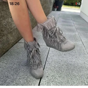 Mockaboots med fransar och kilklack - Snygga boots i mocka med kilklack och massor av fransdetaljer. Skorna har snörning framtill och en rund tå, perfekt för dig som vill sticka ut med din stil. Skriv vid frågor och lämna gärna prisförslag 💞