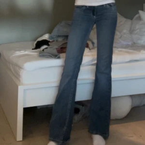 Lowwaist bootcut jeans med broderade fickor - Snygga blå lowwaist jeans med bootcut passform och broderade detaljer på bakfickorna. Jeansen har låg midja och klassisk femficksdesign. Tillverkade i jeansmaterial med lätt tvättad look. Perfekta för dig som gillar en retro vibe och vill sticka ut lite extra.