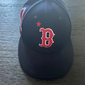 Boston Red Sox keps ASG 2023 - Snygg Boston Red Sox keps från New Era med röd B-logga framtill och broderad ASG 2023 patch på sidan. Kepsen är mörkblå med röda och vita detaljer, klassisk böjd skärm och ventilerande hål. Perfekt för dig som älskar baseball och streetstyle. Helt ny då jag säljer den för att den var för stor. Nypris ligger på 699, pris kan diskuteras vid snabb affär.