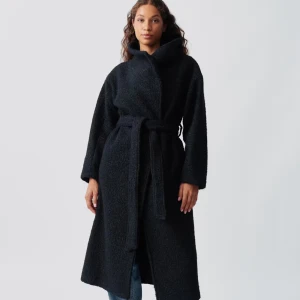 Ginatricot jacka - Säljer en svart lång teddyrock från Weekday med bred krage och knytbälte i midjan. Jackan har en mjuk, fluffig yta och långa ärmar. Perfekt för dig som gillar en oversized look och vill ha något som sticker ut under kalla dagar.