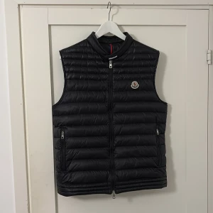 Svart Moncler väst - Säljer nu denna stilrena moncler väst! Skick 9,5/10, ser typ helt ny ut. Storlek 4 men passar M. Självklart Äkta! 