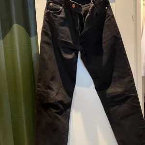 Svarta jeansbyxor från Woodbird - Säljer ett par svarta jeansbyxor från Woodbird i modellen Airport. Byxorna har klassisk femficksdesign, raka ben och normal passform. Tillverkade i bomullsmix med snygg svart tvätt och diskreta detaljer. Perfekta för en clean och stilren look.