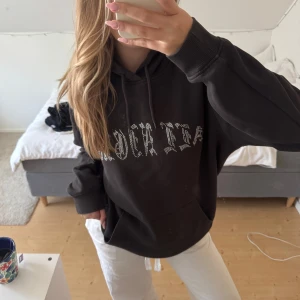 Svart hoodie med tryck och huva - Säljer en svart hoodie med coolt tryck framtill i vita stenar och snörning vid huvan. Tröjan har en klassisk känguruficka och är långärmad med ribbade muddar👙👙