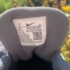 Grå Nike sneakers med vit sula - Säljer ett par grå Nike sneakers med vit sula och mesh-överdel. Skorna har snörning och en klassisk Nike-logga på sidan. Perfekta för vardagsbruk eller träning. Lätta och bekväma med sportig design.