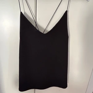 Svart linnetopp med tunna axelband - Säljer en svart linnetopp med tunna axelband som korsas i ryggen. Toppen har en djup v-ringning, den funkar perfekt till sommaren. Den ät XS men passar som S och M, skriv om du  har funderingar eller frågor💕