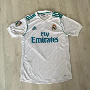 Real Madrid 2018 tröja - Säljer en vit Real Madrid fotbollströja från 2018 av Adidas. Tillverkad i lätt och ventilerande climacool-material. Tröjan är i storlek XL men passar M. ( väldigt liten i storleken ) Pris kan diskuteras. Har du funderingar så är det bara att fråga!