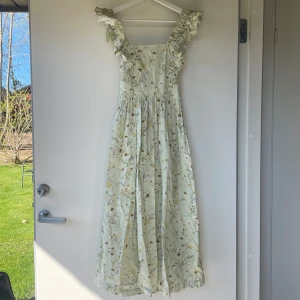 Ljusgrön blommig långklänning från H&M - Superfin ljusgrön långklänning från H&M med blommigt mönster. Perfekt till midsommar!
