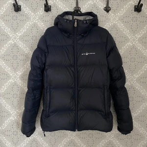 Mörkblå dunjacka från Sail Racing - Säljer en mörkblå dunjacka från Sail Racing i fint skick. Endast använt en säsong. Tecken på användning kan förekomma, men ser inga fläckar eller andra defekter vid inspektion. Skulle säga att den är i mycket bra skick. Storleksmässigt passar den mig som vanligtvis har S/M, och den blir perfekt med en tjocktröja under :) Köpt för 4200:-