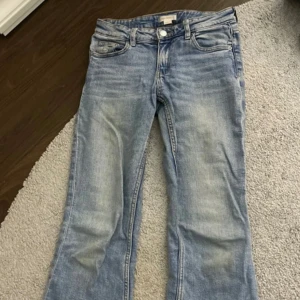 Ljusblå jeansbyxor från Gina Tricot - Ljusblå jeansbyxor från Gina Tricot med klassisk femficksdesign och knappgylf. Byxorna har en lätt utsvängd bootcut-modell och normal passform. Perfekta för en avslappnad stil.