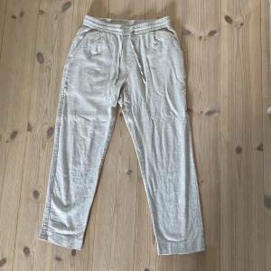 Beige linnebyxor från Zara - Säljer ett par ljusbeige linnebyxor från Zara med snören och sidofickor. Byxorna har en avslappnad passform och är perfekta för varmare dagar. Baktill finns två fickor med knappdetalj. Superlätta och sköna!