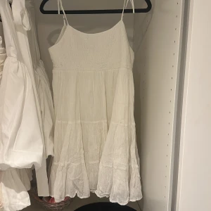 Vit klänning med smock och volang - söt vit klänning med smala axelband och smock upptill. Klänningen har volangdetaljer med smock upptill, slutsåld på Zara 