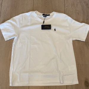 Vit t-shirt från Polo Ralph Lauren - Säljer nu min vita polo Ralph lauren t shirt eftersom den ej kommer till användning och ligger endast i garderoben, tröjan är Aldrgi använd eller tvättad då lappar och tags sitter kvar. Påse medföljer i köper vid önskan! Möts upp i hela Sthlm och fraktar, vid fler frågor kontakta mig mvh Kalle!