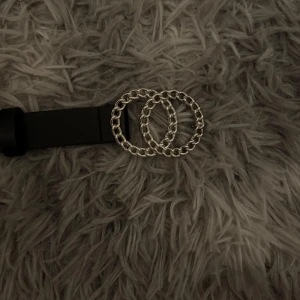 Svart bälte med dubbla silverringar - Snyggt svart bälte med två stora silverfärgade ringar som spänne. Bältet har en stilren design och passar perfekt till jeans eller klänning. Metallringarna har kedjeliknande struktur för en cool detalj.