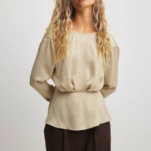 Champagnefärgad blus med draperad rygg från NA-KD - Superfin champagnefärgad blus från NA-KD i storlek 40. Blusen har långärmade ärmar, draperad effekt framtill och en djup v-ringad öppen rygg. Aldrig använd! Nypris 549 kr