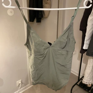 Ljusgrön linnetopp med smala axelband - Säljer en ljusgrön linnetopp med smala, justerbara axelband och v-ringad hals. Toppen är enkel och stilren, perfekt att matcha med jeans eller kjol. Materialet känns mjukt och lätt.