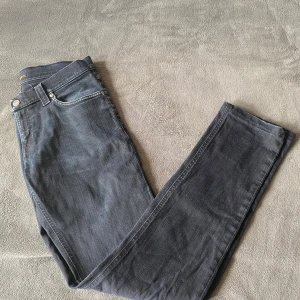 Svarta jeans från Nudie Jeans - Säljer ett par stilrena svarta Nudie Jeans, modell Tight Long John, i storlek 30/34. Grymt sköna och i fint skick  – endast ett litet slitage på en ögla som knappt märks (se bild 5). Nypris ca 1700 kr, mitt pris: 635 kr! Perfekta jeans till sommar o våren och ett riktigt bra pris. Hör av dig vid minsta fråga! Kan sänka priset vid snabb affär🤝🏽
