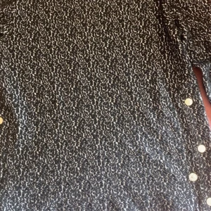 Svartvit mönstrad topp  - Säljer en svartvit topp från 365 Three Sixty Five med abstrakt mönster och dekorativa knappar längs sidan. Topp har en klassisk rund halsringning och är perfekt för dig som gillar stilrena mönster.