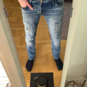 Ljusblå jeans med slitningar  - Ett par ljusblå jeans från Jack and Jones med slitningar. Modellen är Slim fit och jeansen är i mycket bra skick.