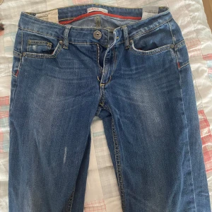 Blå jeansbyxor från Liu Jeans - Säljer ett par klassiska blå jeans från Liu Jeans med snygga gula sömmar och broderad bakficka. Byxorna har normal passform, dragkedja och knapp framtill samt detaljer i läder vid linningen. Perfekta till vardagsstilen!