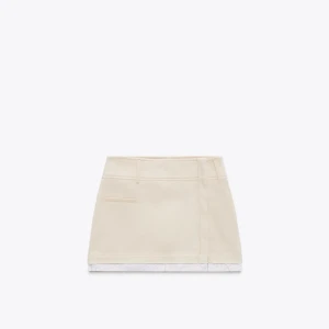 Vit kortkjol med rå kant - Säljer en vit kortkjol med rå, fransig kant nertill. Kjolen har hällor för skärp och en enkel, stilren design utan synliga detaljer framtill. Perfekt för en avslappnad och trendig look.