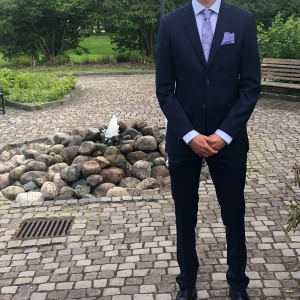 Mörkblå kostym med vit skjorta - Mörkblå kostym från dressman med kavaj och byxor. Kavajen har en klassisk passform. Medföljer en vit skjorta med knappar. Perfekt till skolavslutning, student eller andra fina tillställningar. Storlek 32/34 på byxor. 48 på kavajen. 37/38 på skjortan. Har (m) i vanliga fall på kläder.