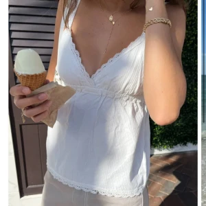 Vit topp med spetsdetaljer - Säljer en söt vit topp med spetsdetaljer från brandy melville. One size men passar mig som oftast bär s i kläder. Toppen är perfekt nu till vår och sommar och passar bra till allt!☀️🩷