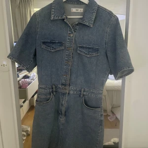 Jeansklänning från MNG - Säljer en snygg jeansklänning från MNG med korta ärmar och knappar framtill. Klänningen har två bröstfickor med lock och två fickor vid höfterna. Perfekt för en avslappnad stil. och till sommarkvällar🙏🏻💕