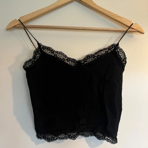 kort spetslinne från ONLY - kort svart spetslinne, använd några gånger men som ny. sitter tajt och storleken har skavts bort men skulle tro XS/S. längd inkl axelbanden - 42 cm, bredd - ca 30 cm
