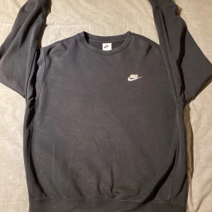 Svart sweatshirt från Nike - Säljer en klassisk svart sweatshirt från Nike med deras ikoniska logga på bröstet. Tröjan har en rund halsringning och långa ärmar, perfekt för en avslappnad stil. Passar bra till både jeans och träningsbyxor. Kan gå ner i pris vid snabb affär