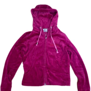 Rosa juicy velour hoodie - Säljer en snygg rosa velourjacka från Juicy Couture med huva och dragkedja. Jackan har broderad logga på bröstet och ryggen, samt snörning i huvan.