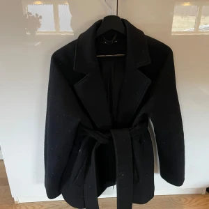 Svart kappa med bälte - En svart kappa i kort modell med midjeband från Gina tricot. Väll använd🥰