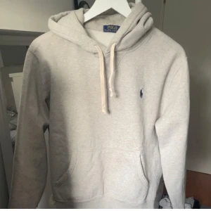 Grå hoodie från Polo Ralph Lauren - Säljer en stilren grå hoodie från Polo Ralph Lauren. Den är storlek M men passar även S pga att den är lite feltvättad. Perfekt för en avslappnad stil. Inga problem med den alls, nyköpt men säljer pga att den var för liten för mig. 😉