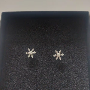 Snöflingeformade örhängen i silver - Säljer ett par eleganta örhängen i form av snöflingor. De är tillverkade i silver och har en glittrig yta som fångar ljuset vackert.❄️