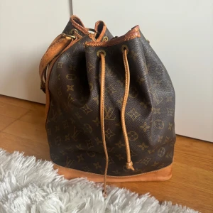 Noé cloth handbag från Louis Vuitton - Säljer en klassisk brun  från Louis Vuitton med det ikoniska monogrammönstret. Väskan har en praktisk dragsko och detaljer i läder. 