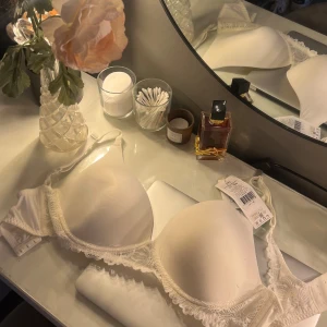 Vit spets-bh - Elegant vit bh med spetsdetaljer längs kanterna. Den har en slät yta och justerbara axelband för perfekt passform. Helt oanvänd och är i nyskick!!🤩🤩💌💌