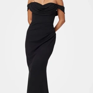 Svart offshoulder långklänning - Elegant svart långklänning med offshoulder-design och draperad överdel. Perfekt för en stilfull kväll.