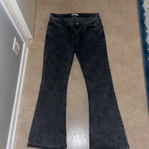 Svarta bootcut jeans - Snygga gråa bootcut jeans med klassisk femficksdesign och knappgylf. Perfekta för en avslappnad stil. 