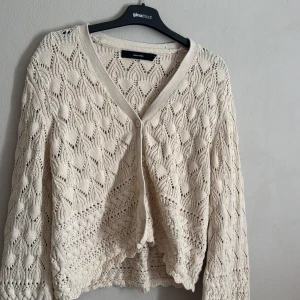 Beige stickad kofta från Vero Moda - Säljer en fin beige stickad kofta från Vero Moda med v-ringning och knapp framtill. Perfekt för lager-på-lager och ger en mysig känsla. Passar bra till både jeans och kjol.