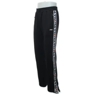 Fila svarta träningsbyxor strl M - Snygga svarta träningsbyxor från Fila med logotyp längs sidorna. Byxorna har en elastisk midja och raka ben, perfekta för en sportig look. De är tillverkade i ett bekvämt syntetmaterial. Ett par svarta träningsbyxor med FILA logga längs sidan av benen. Byxorna har en resår i midjan och en liten FILA logga på vänster ben och fickorna har dragkedja med Fila foga i metall. Dragkedja finns och längs ned på benen om man vill ha med utslängda ben.