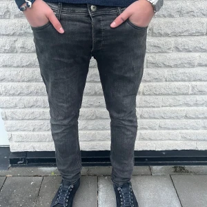 Jack and Jones jeans  - Snygga svarta jeansbyxor med en tight passform. De har en klassisk femficksdesign och en knappgylf. Perfekta för en stilren look. Modellen är 185 70 kg 
